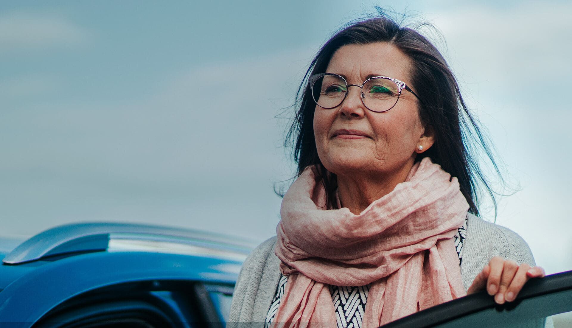 Nainen seisoo auton vieress&auml; ulkona